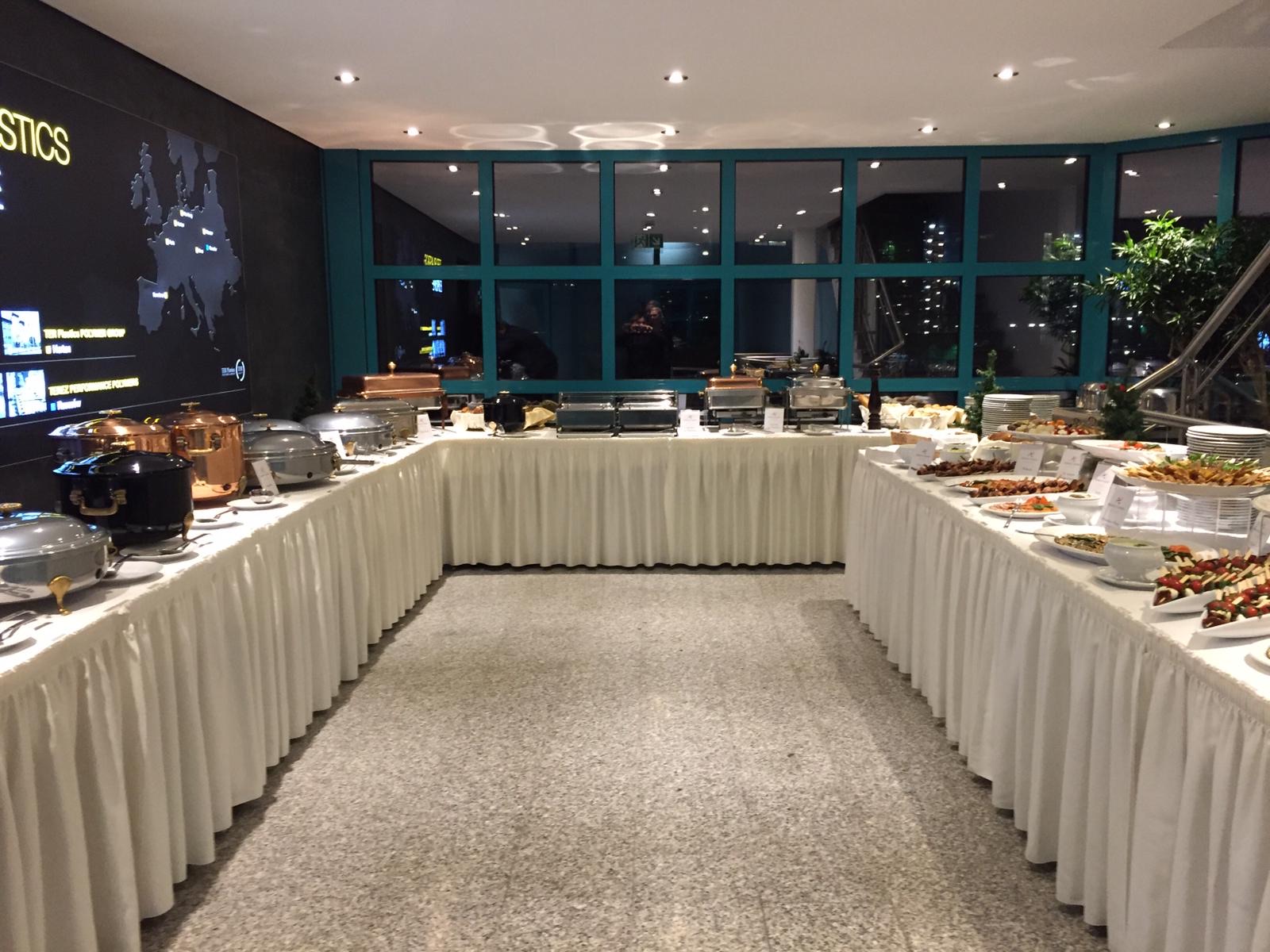 Weiße Tellerstapel stehen auf einem floralen Buffet-Tisch.