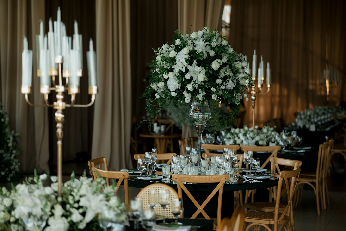 Elegante runde Tische für eine Veranstaltung mit floralen Mittelstücken und goldenen Kandelabern.